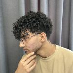 تصویر یک پسر است که در سالن زیبایی موهایش فر کرده است. آکادمی و آرایشگاه محمد فرشته